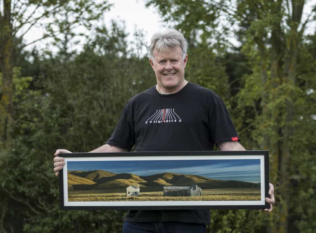 NZIPP Grand Master Tony Stewart holds fine art framed print made by Queensberry.