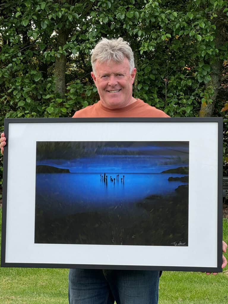 Tony Stewart holds framed photograph ready to display.