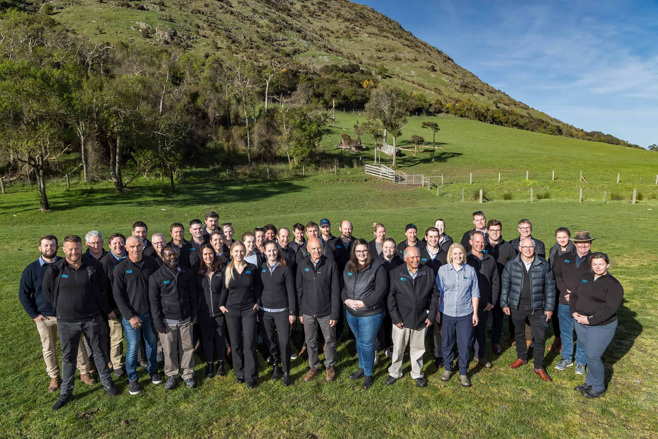 Rural delegation pose as a group out in a paddock.