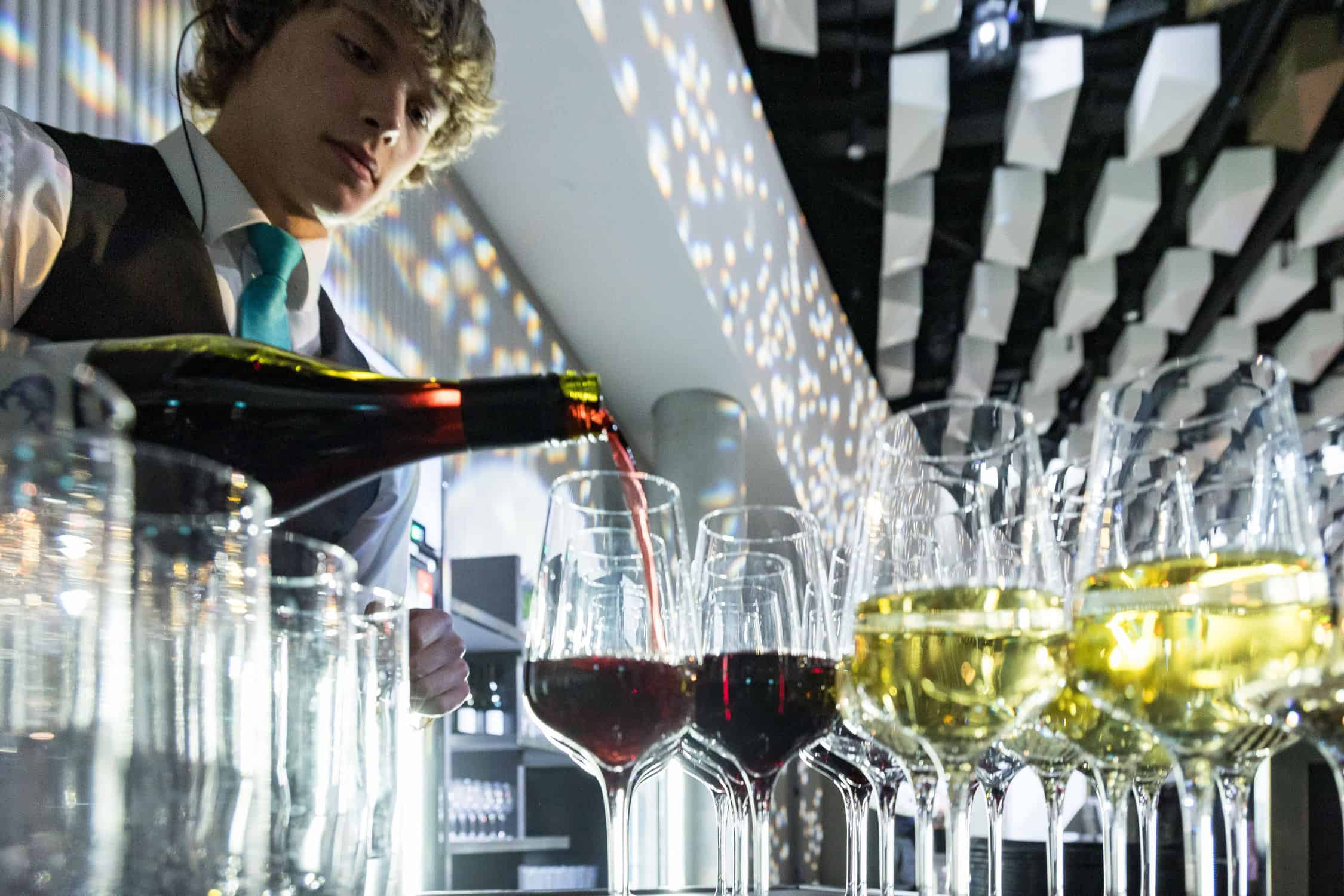 Waiter pours wine ahead of client function opening, Te Pae.