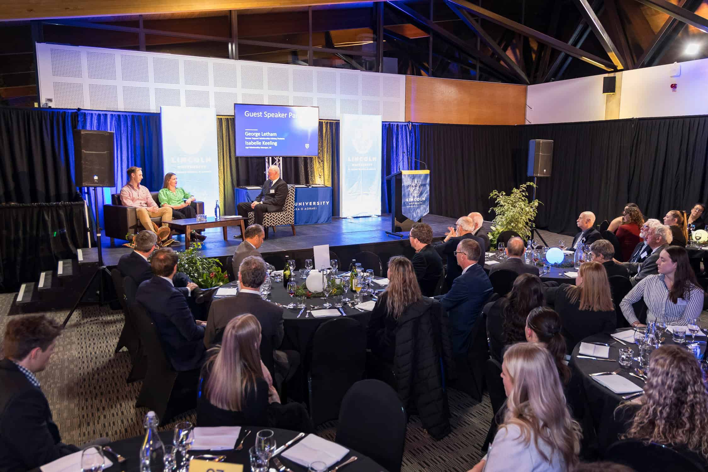 Speaker panel on stage during a industry discussion.