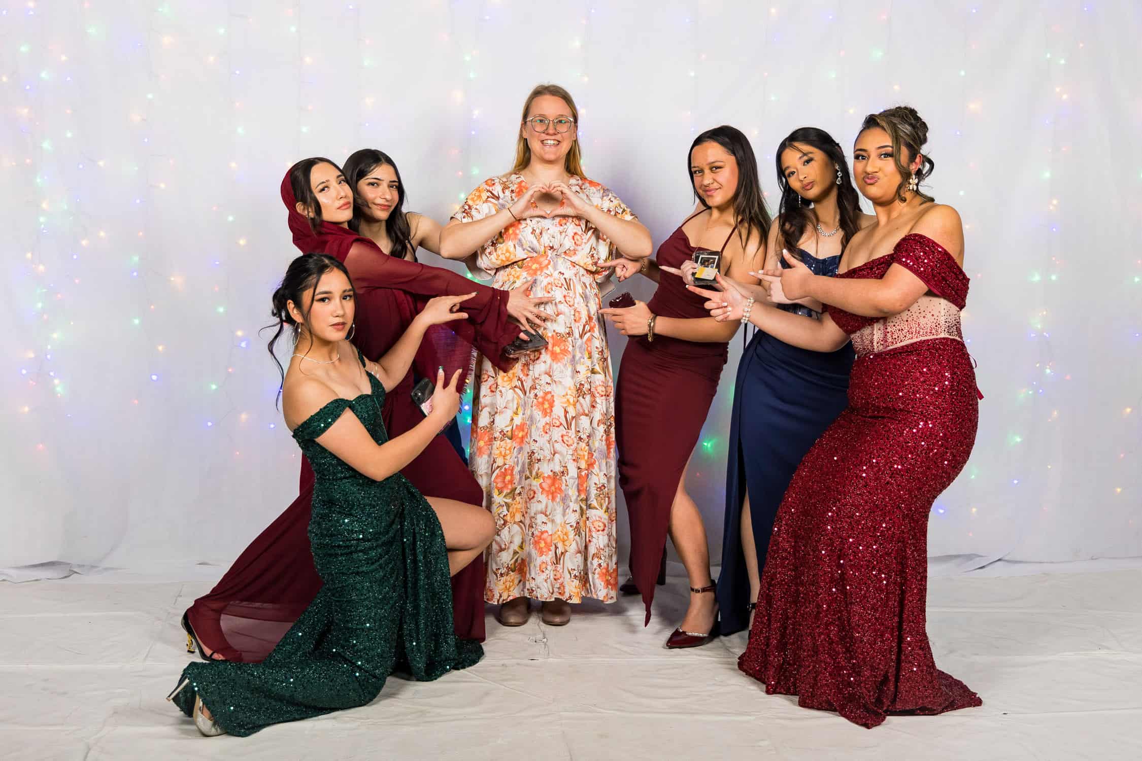 Girls having fun at school ball, posing on white backdrop.