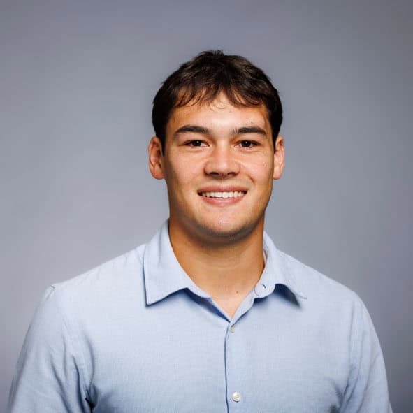 Arborist poses for profile photo in full PPE and rope harness.